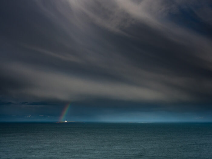 Travel photography Scotland: A rainbow frames Muckle Skerry Lighthouse in the Pentland Firth, near John o' Groats, Scotland.