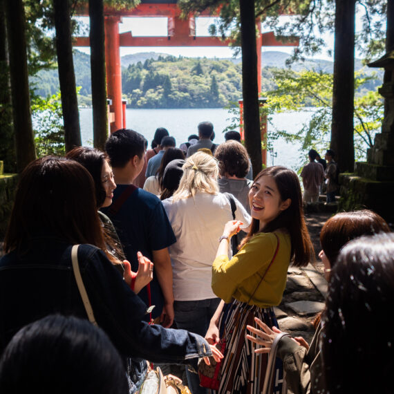 Tourists stand in line for selfies at the famous red lakeside torii (gate) at at the Hakone Shrine, Lake Ashi, Hakone, Japan.