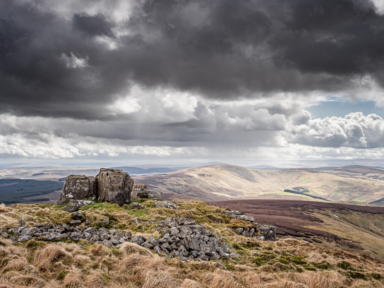 Distant storms seen from Auchope Cairn, a hill on the Pennine Way long-distance footpath through the Cheviot Hills on the border between England and Scotland on 26 April 2018.